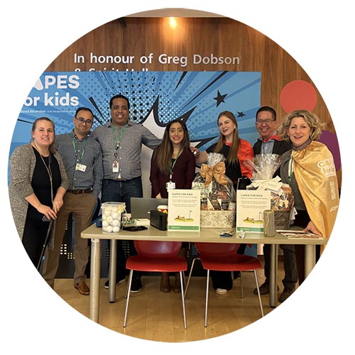 A group of staff and visitors from The Well promoting the annual Capes for Kids fundraising campaign.