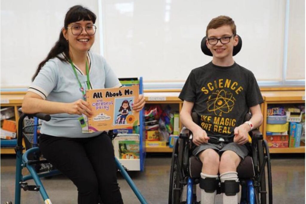 An adult holding a book, and a child sitting on a wheelchair