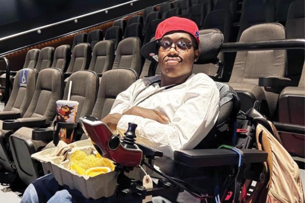 A teen sitting on a wheelchair in a cinema