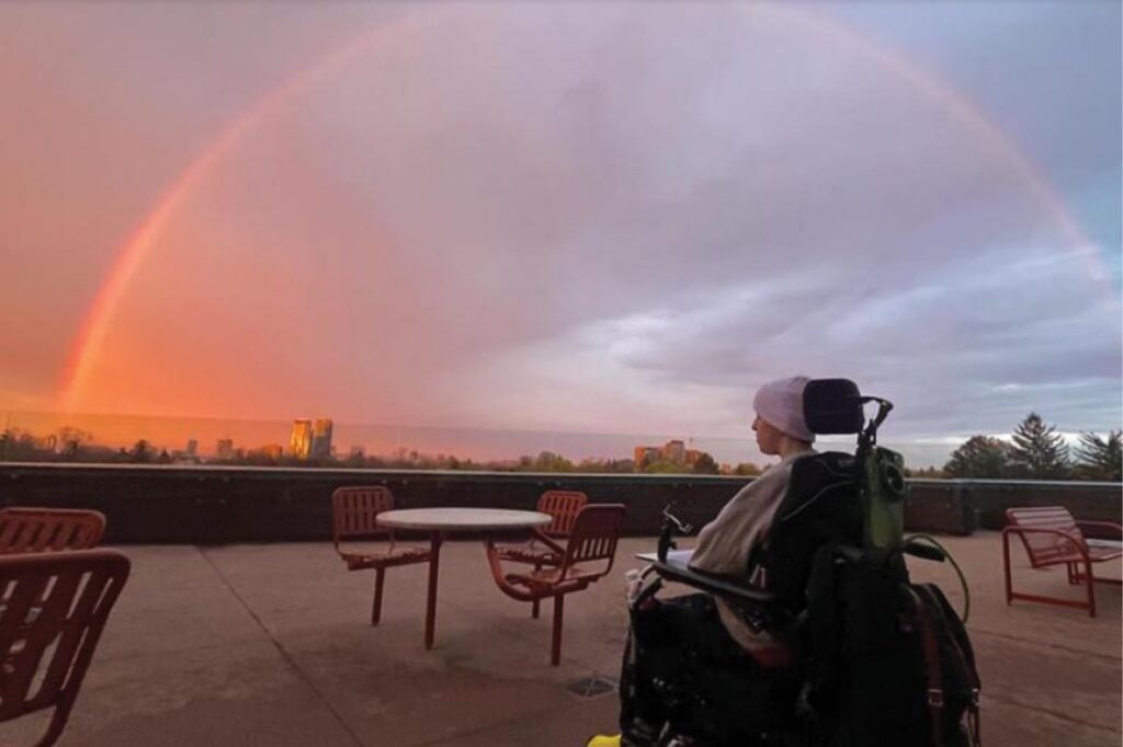 A teen sitting on a wheelchair and looking at the sky