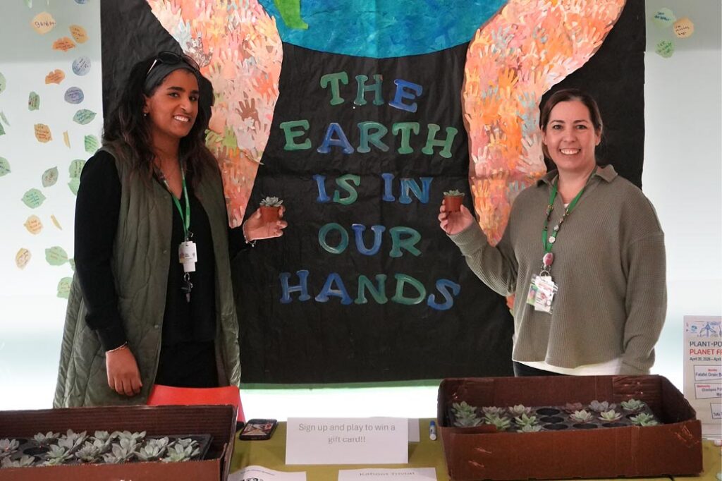 Two people standing in front of a setup with the word "the earth is in our hands"